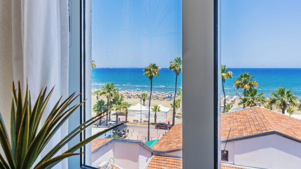 A view of a beach with palm trees and a clear blue sky. - Whispering Palms 1-BR Apt. By Finikoudes Beach (Larnaca)
