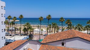 A coastal view with a beach, palm trees, and a clear blue sky. - Whispering Palms 1-BR Apt. By Finikoudes Beach (Larnaca)