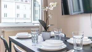 Una mesa de comedor dispuesta con platos, vasos y una orquídea en maceta.