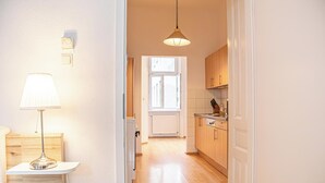 Una cocina luminosa con armarios de madera, una lámpara colgante y un ventanal que deja entrar luz natural.