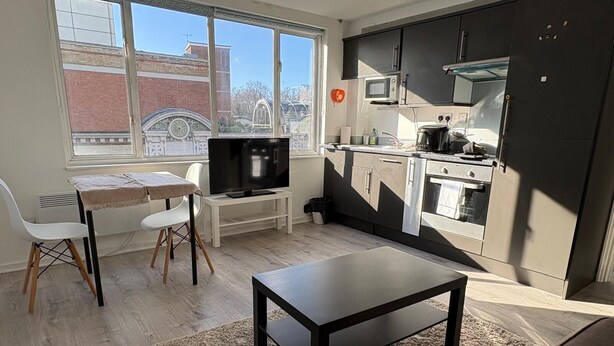Un espace de vie compact comprenant un coin cuisine, un coin repas avec une table et des chaises, et un téléviseur.