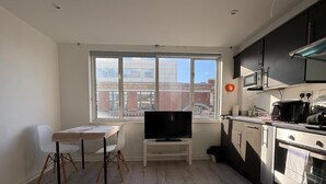 Une cuisine compacte équipée d’un téléviseur, d’une table à manger et de chaises.