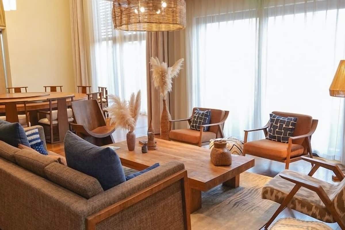 A modern living room with a sofa, armchairs, a coffee table, and a dining area with chairs and a table.