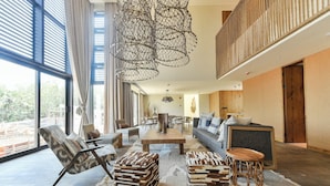 Ein geräumiges Wohnzimmer mit großem Fenster, einem Holztisch und einem modernen Kronleuchter.