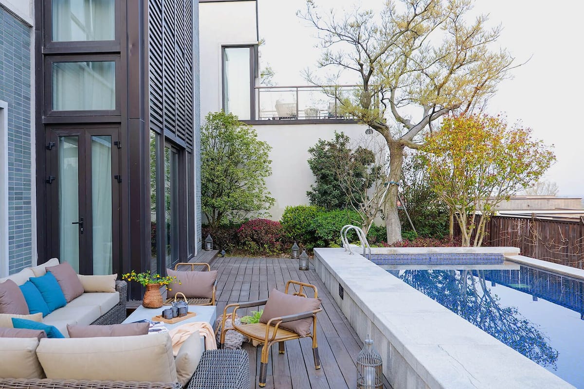 A modern outdoor living area with a pool, a sofa, and a dining table.