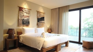 Ein geräumiges Schlafzimmer mit einem großen Bett, zwei Wandlampen und Blick auf Grün durch ein großes Fenster.