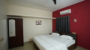 A bedroom with a bed, a wardrobe, a wall-mounted air conditioner, and a door. - Hotel Zen zones  (Chennai)