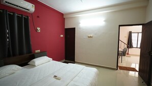 A hotel room with a bed, a red wall, an air conditioning unit, and a door leading to a balcony. - Hotel Zen zones  (Chennai)