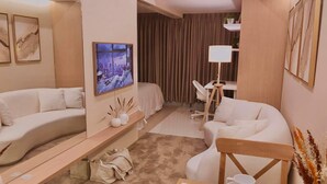 Een moderne hotelkamer met een bank, een eettafel gedekt met borden en bestek, een lamp en een stadsgezichtschilderij aan de muur.