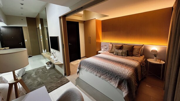 Een moderne hotelkamer met een groot bed, nachtkastjes, een televisie en een badkamer met een spiegel en wastafel.