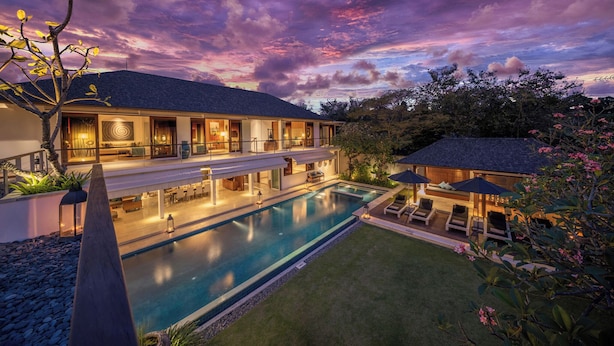 A modern hotel with a pool, outdoor seating, and a well-lit interior. - Cendrawasih Villa Seminyak  (Seminyak)