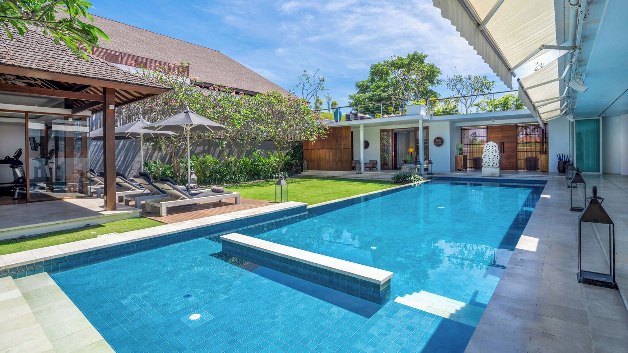 A modern swimming pool with a sun terrace, exercise equipment, and a well-maintained garden.