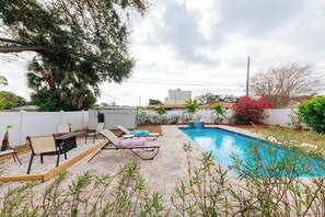 Ein Garten mit Swimmingpool, Liegestühlen und einem kleinen Gartenhaus.