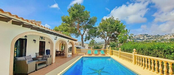 A poolside area with a pool, lounge chairs, and a view of the landscape. - Villa Hermosa Joya - Moraira, Costa Blanca (Moraira)