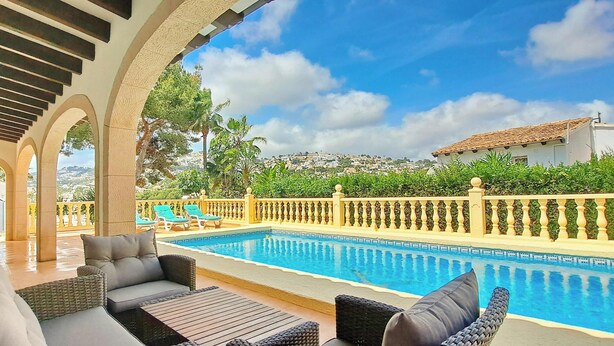 Zona de piscina con asientos al aire libre, vista despejada a la piscina y un paisaje urbano distante.
