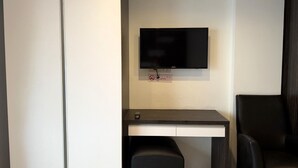 Une chambre moderne dotée d’un téléviseur à écran plat fixé au mur, d’un bureau avec une chaise et d’un banc.