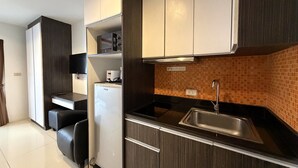 Une cuisine moderne avec des meubles de couleur bois foncé, un réfrigérateur blanc, un four encastré et un pare-feu en carreaux.
