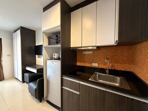Eine moderne Küche mit dunklen Holzschränken, einem weißen Kühlschrank, einem eingebauten Backofen und einer gefliesten Spritzschutzwand.