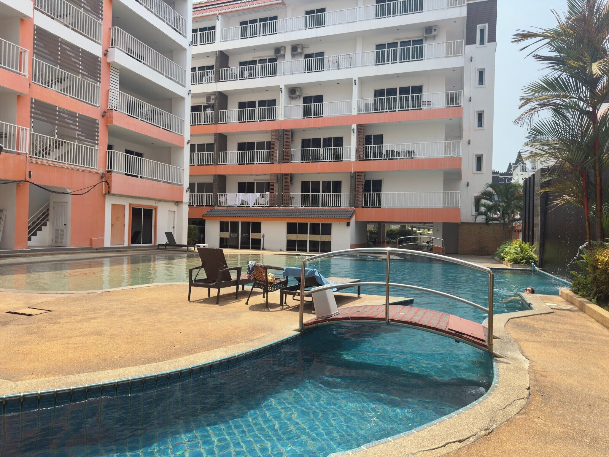 A multi-story hotel with a swimming pool, outdoor seating, and balconies.
