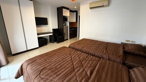 Une chambre d’hôtel avec deux lits, un bureau, une chaise, une télévision et une kitchenette.