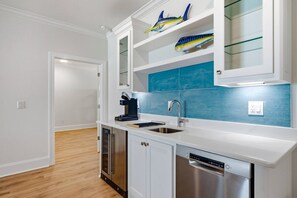 Una cocina moderna con armarios blancos, lavavajillas de acero inoxidable y salpicadero azul.