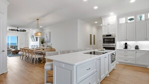 A modern kitchen with white cabinetry, a central island, and built-in appliances. - Brand-New Oceanfront Showstopper | 6 En-Suite Bedrooms, Pool, 2 Hot Tubs, Elevator (North Myrtle Beach)