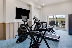A gym with cardio equipment, a TV, and a view of the outdoors. - Brand-New Oceanfront Showstopper | 6 En-Suite Bedrooms, Pool, 2 Hot Tubs, Elevator (North Myrtle Beach)