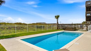 A rectangular swimming pool with a white fence surrounding it, a palm tree, and a lounge chair. - Brand-New Oceanfront Showstopper | 6 En-Suite Bedrooms, Pool, 2 Hot Tubs, Elevator (North Myrtle Beach)