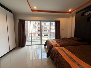 A hotel room with a large bed, a sliding glass door to a balcony, and a view of a building with balconies. - Pool-view Studio With Balcony - Nordic VIP 3, Pratumnak (Pattaya)