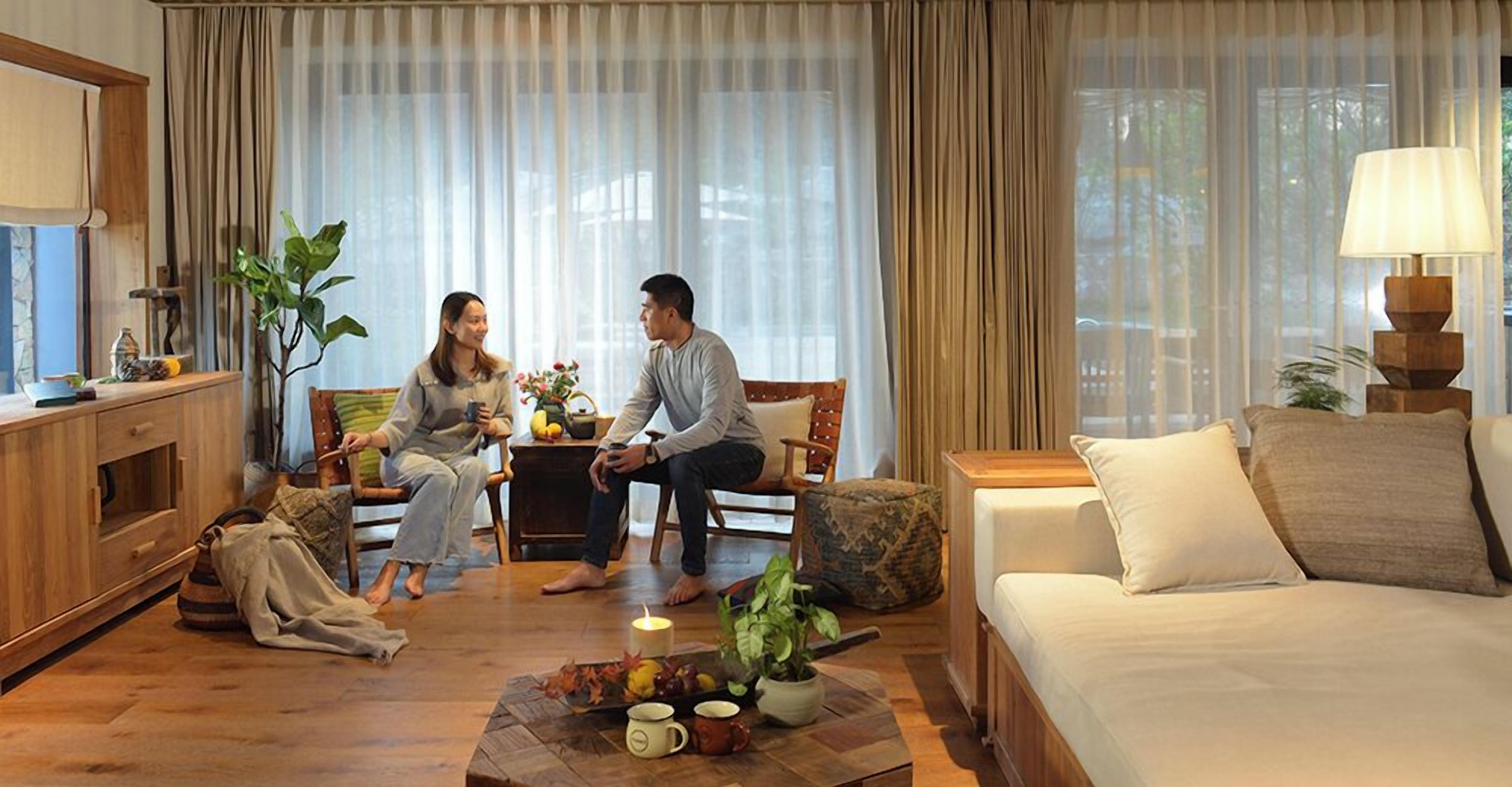 A cozy living room with a sofa, a coffee table with fruits and a candle, and a TV on a wooden cabinet.
