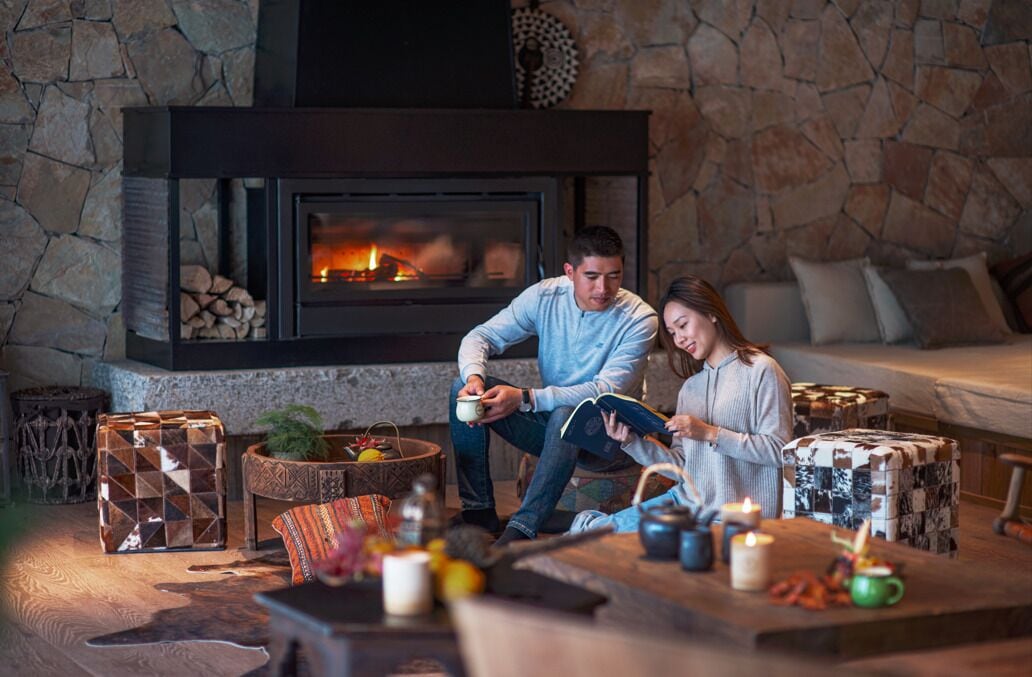 A cozy living room with a fireplace, a sofa, and a coffee table with various items.