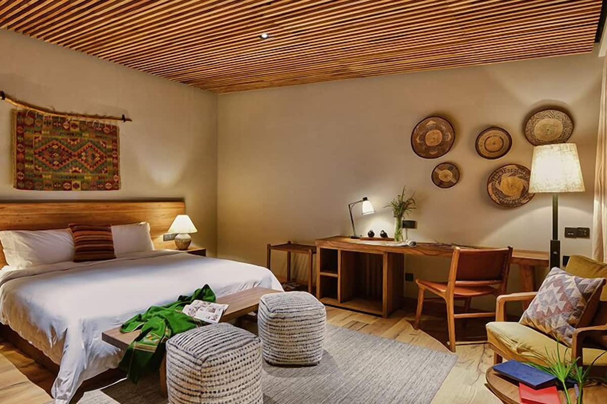 Una habitación de hotel con una cama de madera, un escritorio, una silla y una pequeña mesa.