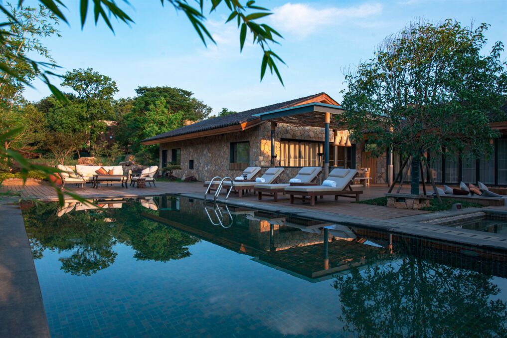 Un área de piscina con sillas de descanso y un edificio de piedra.