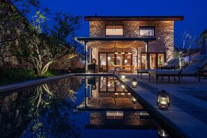 A modern house with a stone facade, a swimming pool, and outdoor seating. - naked Hill (Nanjing)