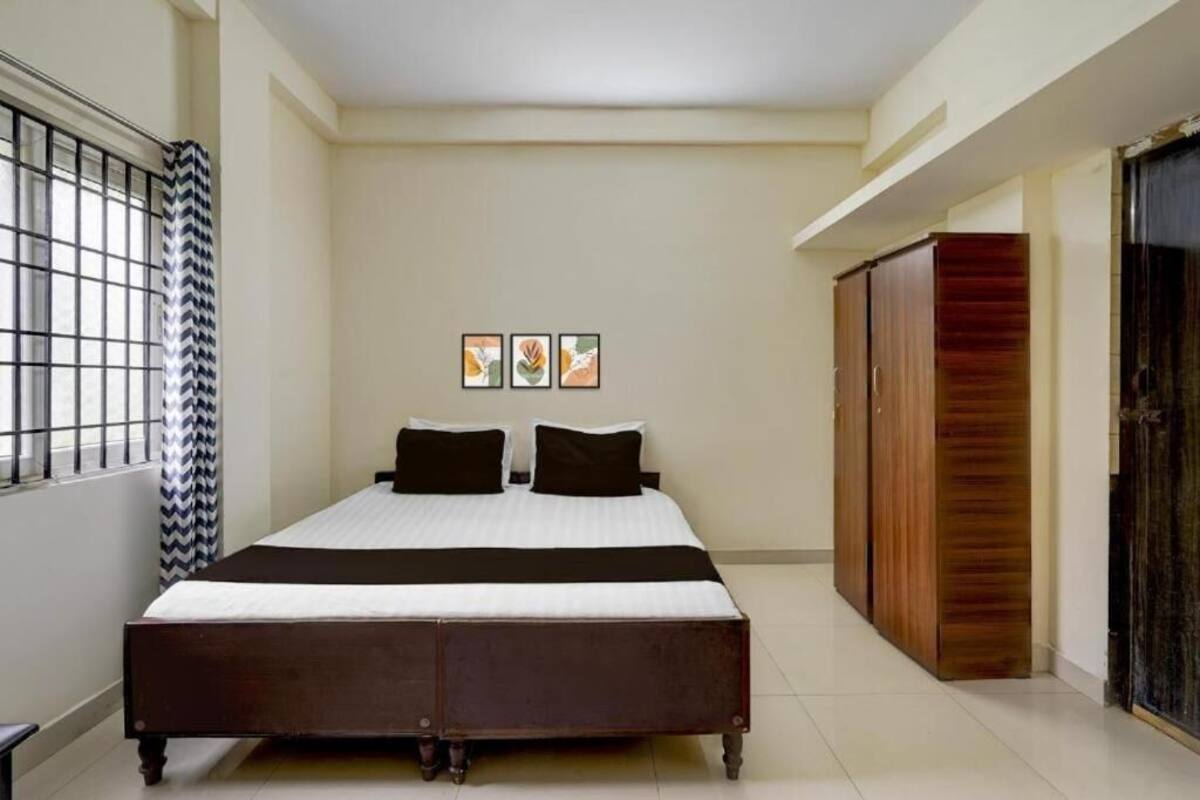 A bedroom with a bed, a wardrobe, and three framed pictures on the wall.