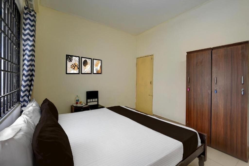 A bedroom with a bed, a wardrobe, a nightstand, and wall art.