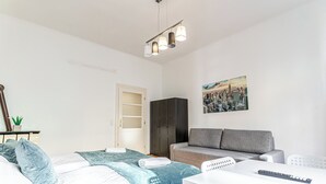 Ein modernes Schlafzimmer mit einem Bett, einem grauen Sofa, einem weißen Tisch und einem Stadtbild.