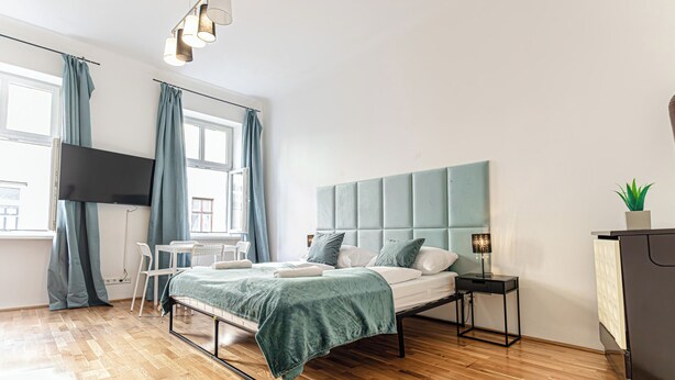 Ein modernes Schlafzimmer mit Bett, Schreibtisch, Fernseher und Kommode.