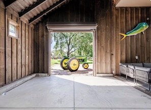 Une grange avec une grande porte ouverte, un tracteur à l’extérieur et un décor en forme de poisson accroché au mur.