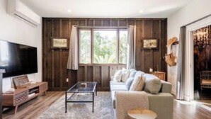 Un salon moderne avec un canapé, une table basse, un téléviseur et des murs en bois.