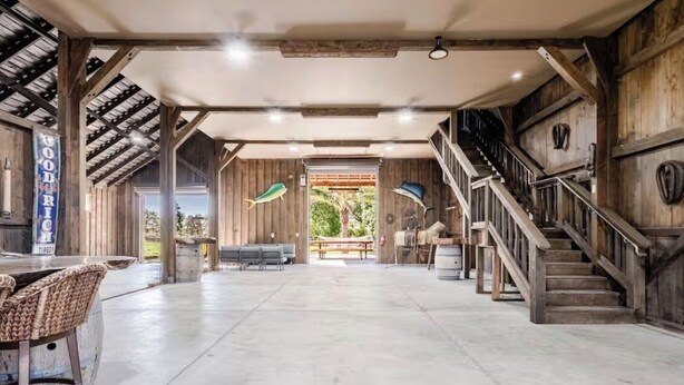 Un intérieur spacieux avec un plafond haut, un escalier et une vue sur l’extérieur, visible à travers une porte.