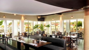 Un restaurante con amplios ventanales, mesas de madera y asientos de cuero negro.