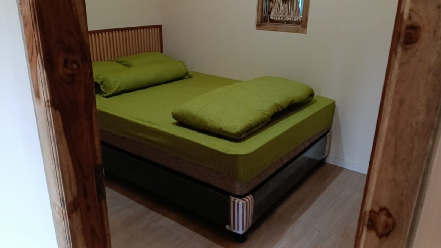 Un lit simple avec une tête de lit en bois et un matelas vert.