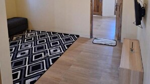 A hallway with a patterned rug, a wooden bench, and a door leading to another room. - Surya Bromo Homestay (Ngadisari)