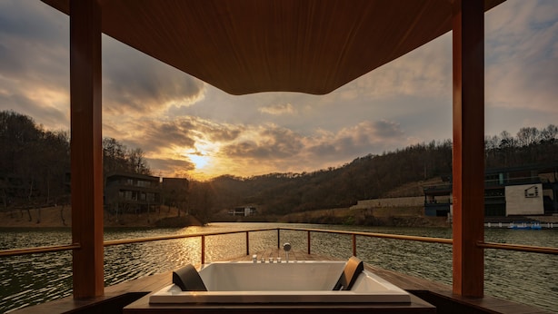 A wooden deck with a hot tub overlooking a river. - naked Home GRAND Ginkgo Valley (Xiaogan)