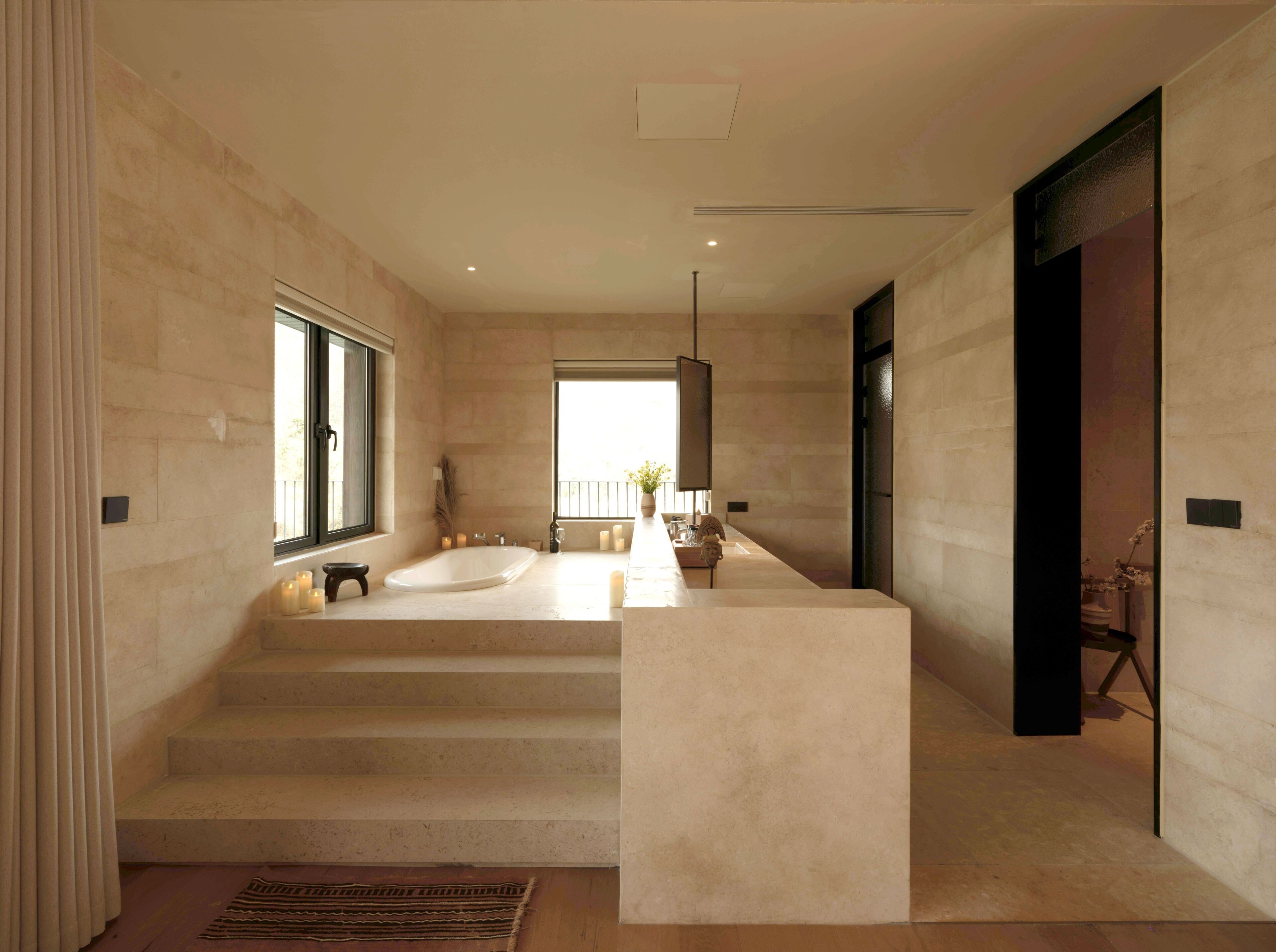 Ein modernes Badezimmer mit einer großen Badewanne, einem Waschtisch und einem Fenster für natürliches Licht.
