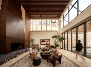 A spacious lobby with a fireplace, comfortable seating, and large windows offering views of the outdoors.