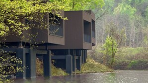 A modern houseboat with a balcony, situated on a calm river surrounded by lush greenery. - naked Home GRAND Ginkgo Valley (Xiaogan)