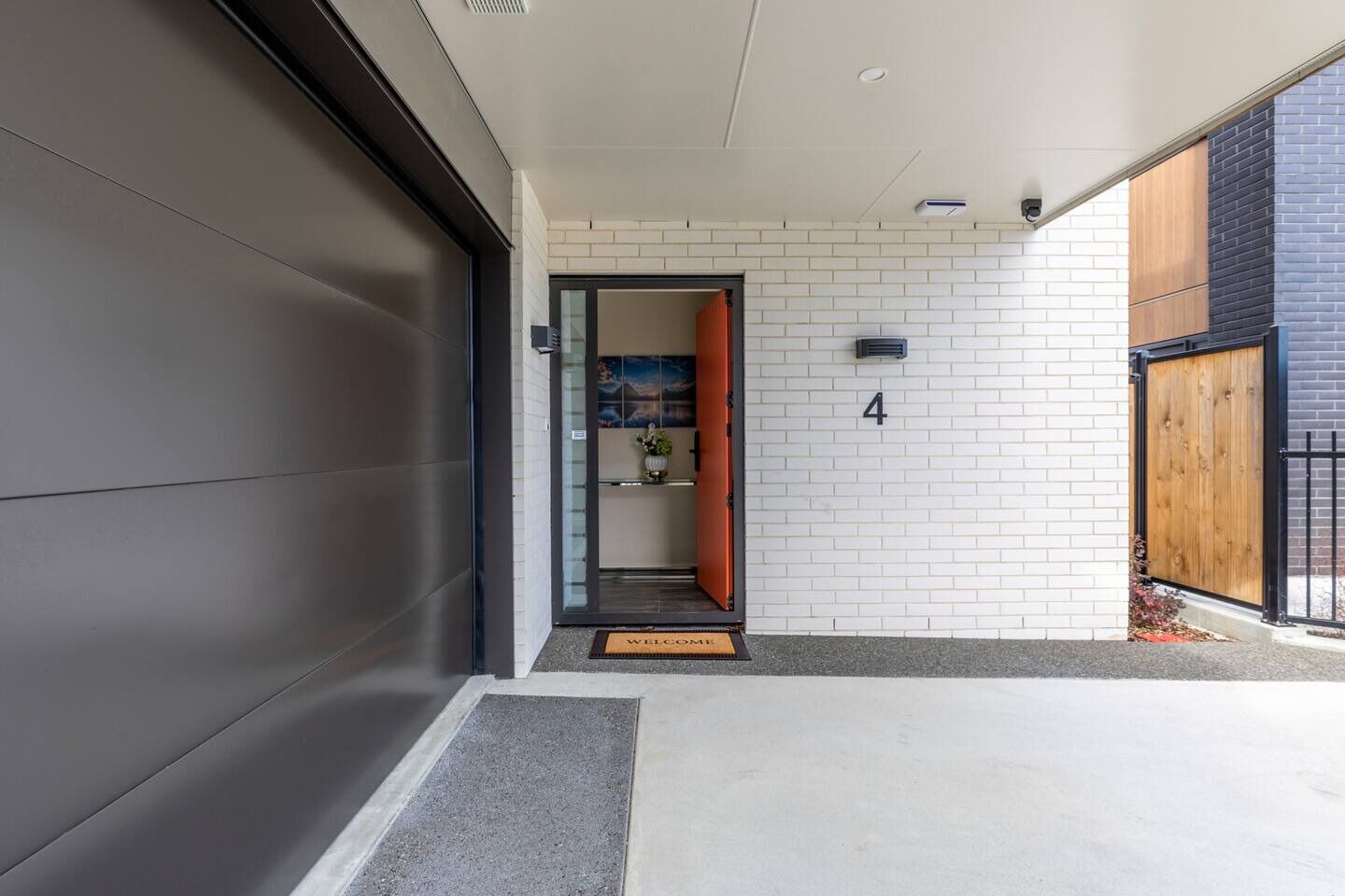 A modern building entrance with a garage door, a welcome mat, and a number '4' on the wall.