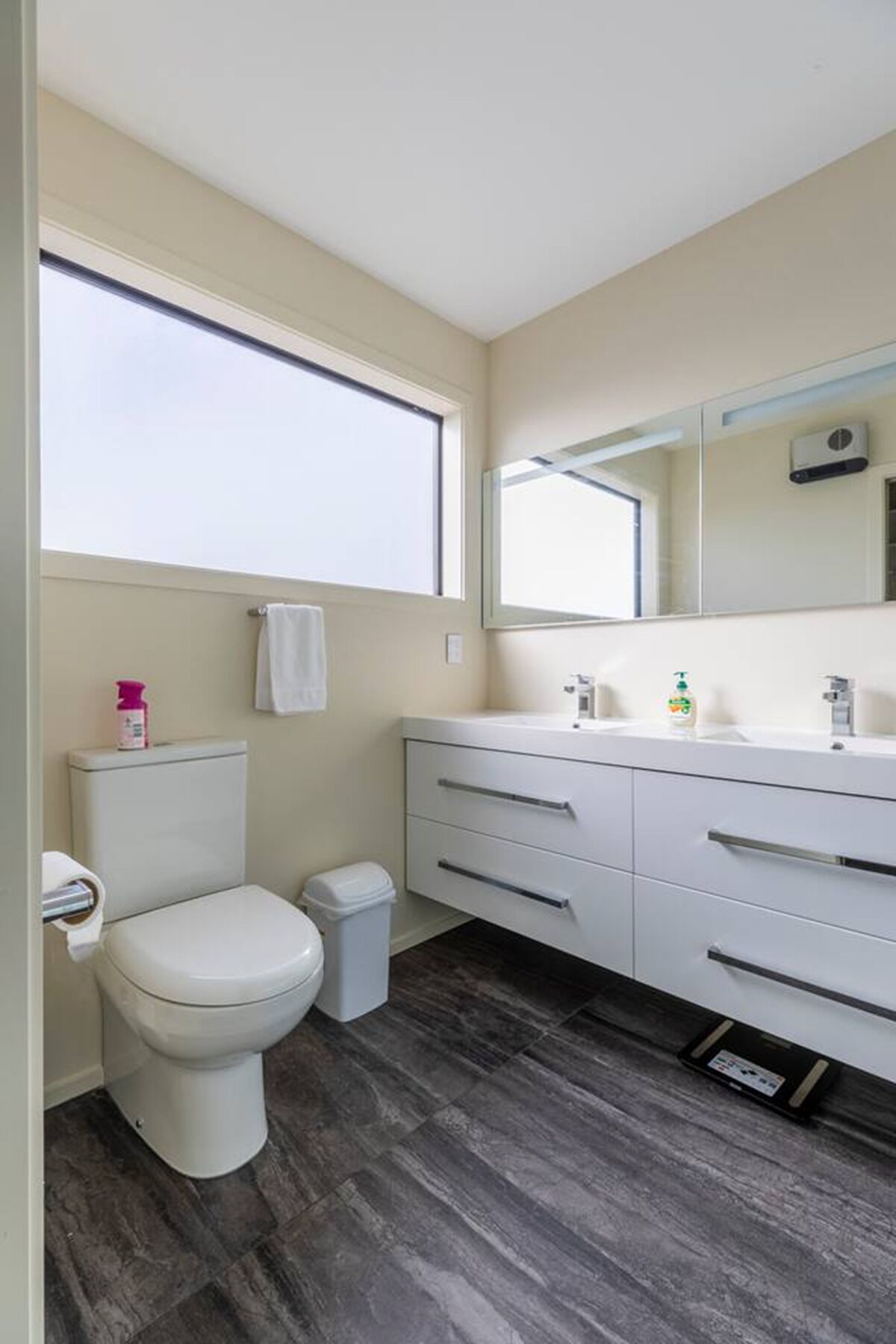 Un bagno moderno con il water, un lavandino con uno specchio e una finestra.